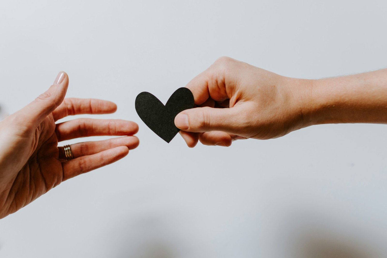 Dos manos que se acercan con un corazón de papel